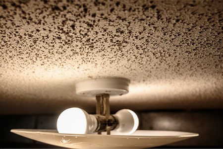A ceiling light that shows the popcorn ceiling
