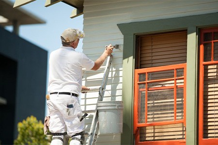 A contractor painting the exterior of a house