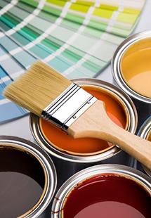 a paintbrush atop several paint cans