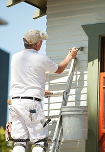 a contractor painting the exterior of a house