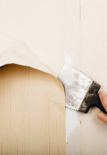 a contractor removing wallpaper from the wall