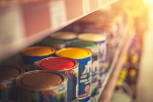 a line of paint cans on a shelf at a paint store